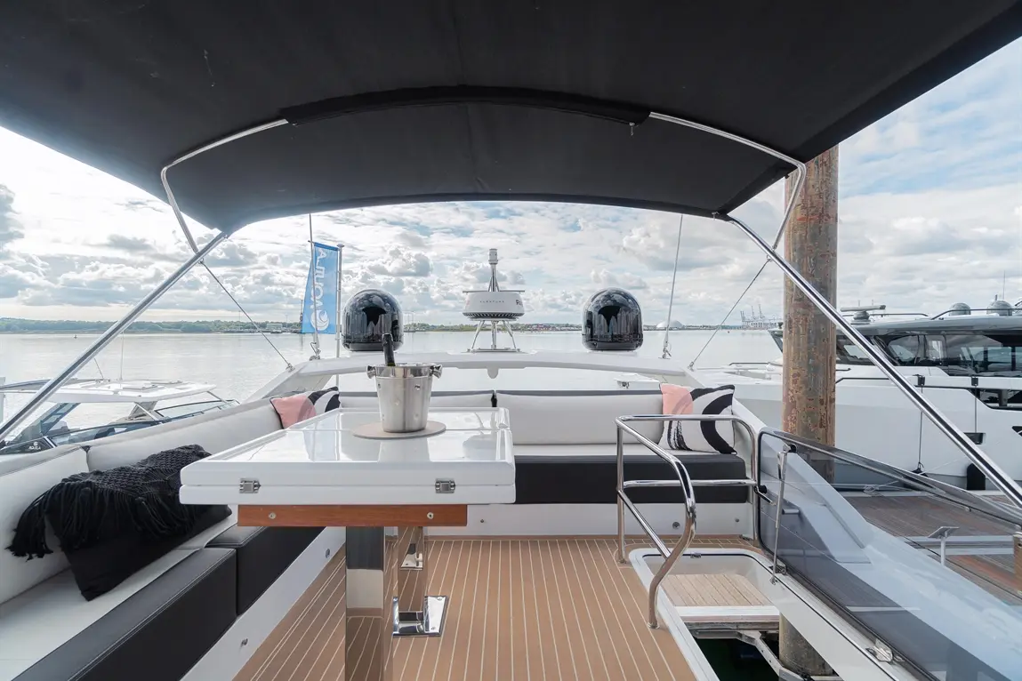 Luxury yacht interior featuring a table with a champagne bucket, plush seating, and panoramic views of the water.